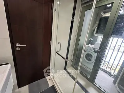 Modern bathroom with glass shower and washing machine on balcony.