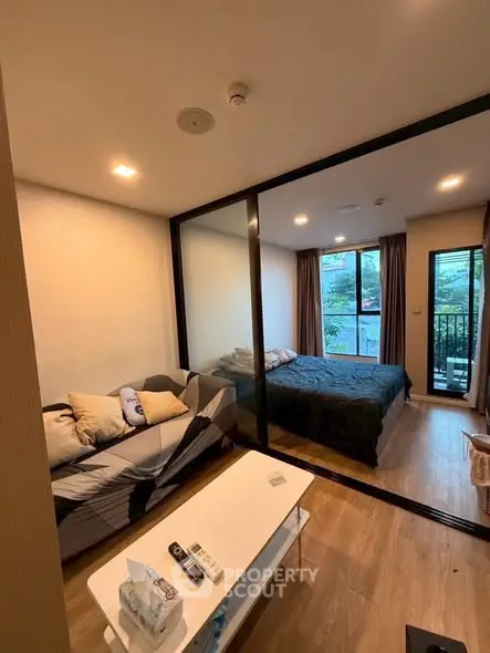 Modern studio apartment with glass partition, cozy living area, and natural light from large windows.