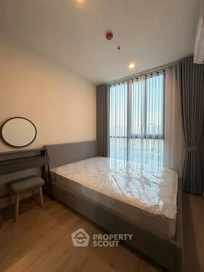 Modern bedroom with large window and stylish furnishings in a cozy apartment.
