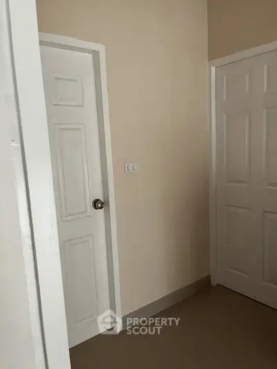 Minimalist hallway with two white doors and beige walls