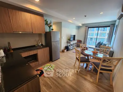 Modern open-layout kitchen and living room with wooden flooring and natural light.