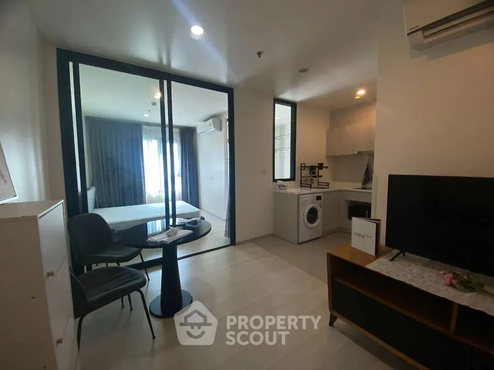 Modern apartment with open layout, featuring a cozy living area, compact kitchen, and glass-walled bedroom.