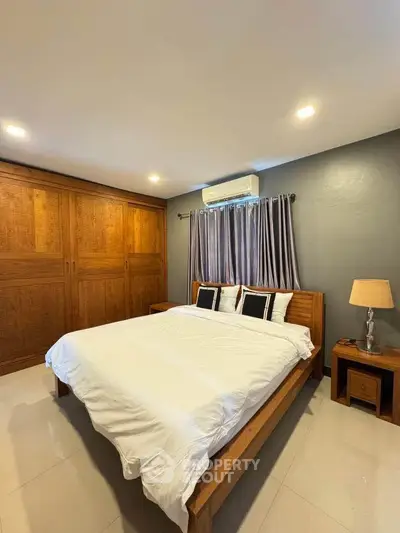 Spacious bedroom with wooden furniture and modern lighting