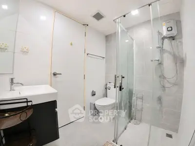 Modern bathroom with glass shower and sleek fixtures in contemporary apartment.