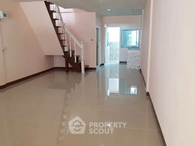 Spacious open-plan interior with glossy tiled floors and elegant staircase, perfect for modern living.