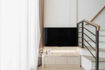 Modern living room with sleek TV setup and elegant staircase design