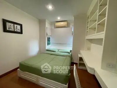 Cozy bedroom with green bedding and built-in desk, ideal for comfortable living.