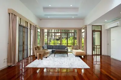 Spacious living room with elegant hardwood floors and large windows overlooking lush greenery.
