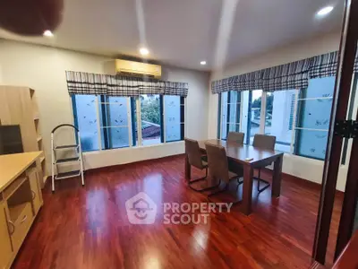 Spacious living room with hardwood floors and large windows offering natural light and a cozy dining area.