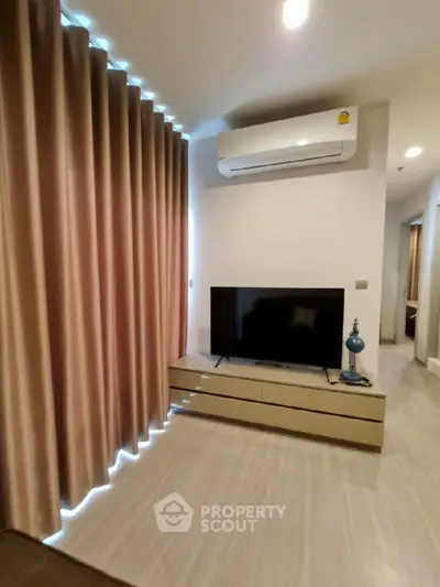 Modern living room with sleek TV setup and elegant curtains, featuring air conditioning for comfort.
