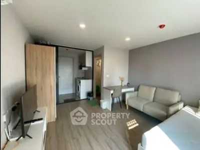 Modern studio apartment with cozy living area and compact kitchen, featuring sleek furniture and bright lighting.