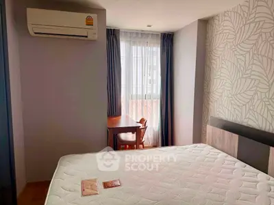 Cozy bedroom with air conditioning and natural light, featuring a stylish accent wall and a compact study area.