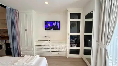 Modern bedroom with built-in wardrobe and TV, featuring a washing machine in the corner.