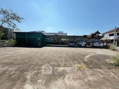 Spacious outdoor parking area with covered carports and surrounding buildings under clear blue sky.