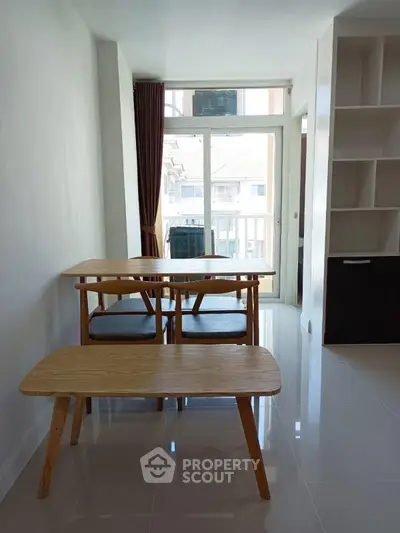 Bright dining area with modern wooden table and chairs, large window, and built-in shelving.