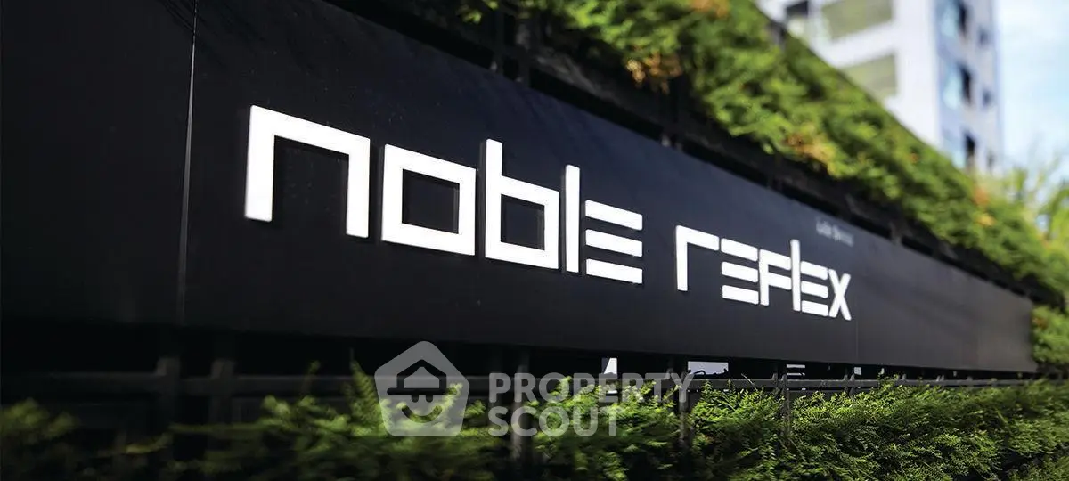 Modern building exterior with lush greenery and sleek signage, showcasing urban sophistication.