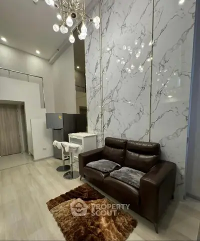 Luxurious modern living room with marble accent wall and elegant chandelier