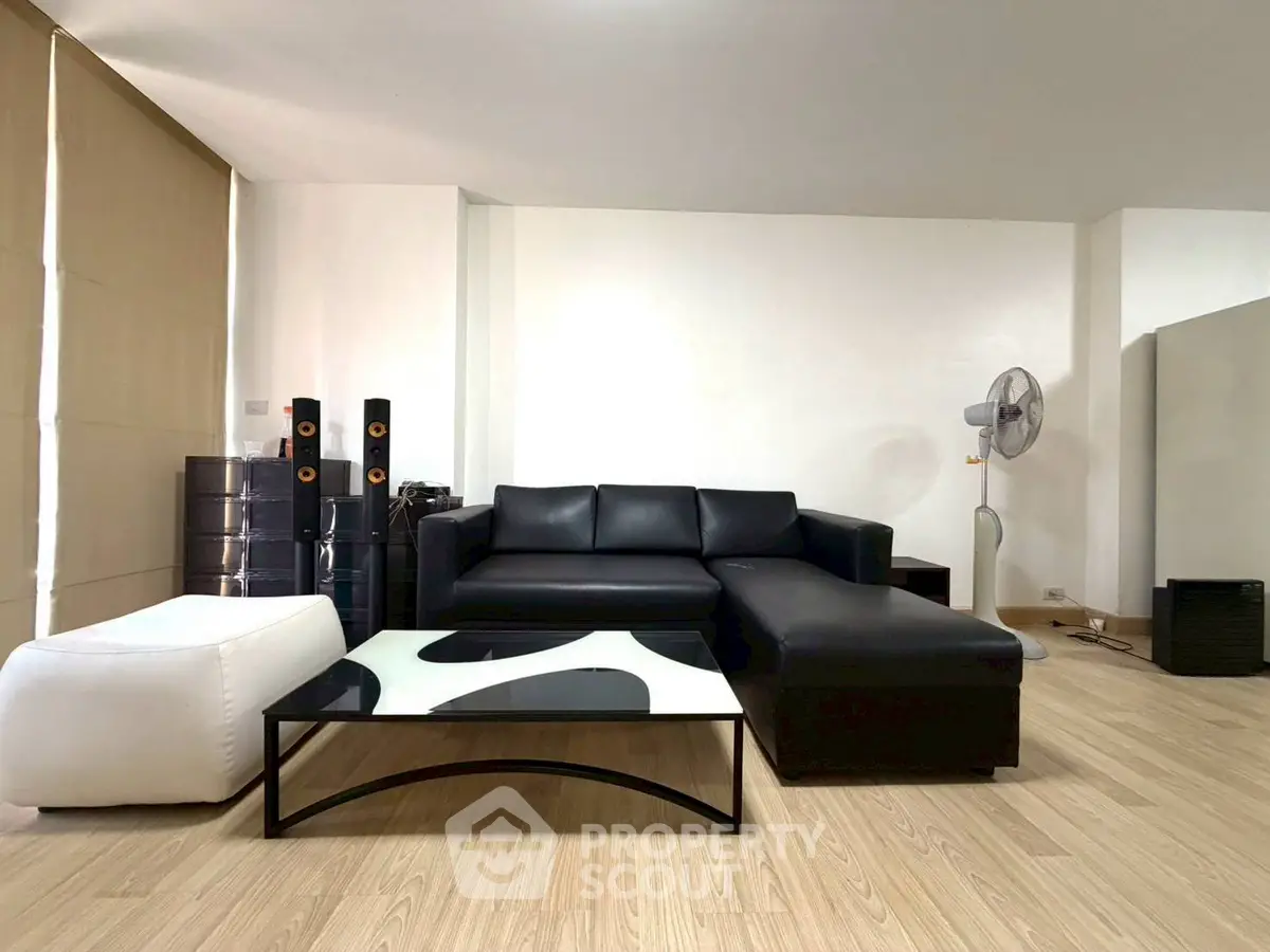 Spacious modern living room with sleek black leather sofa and stylish decor