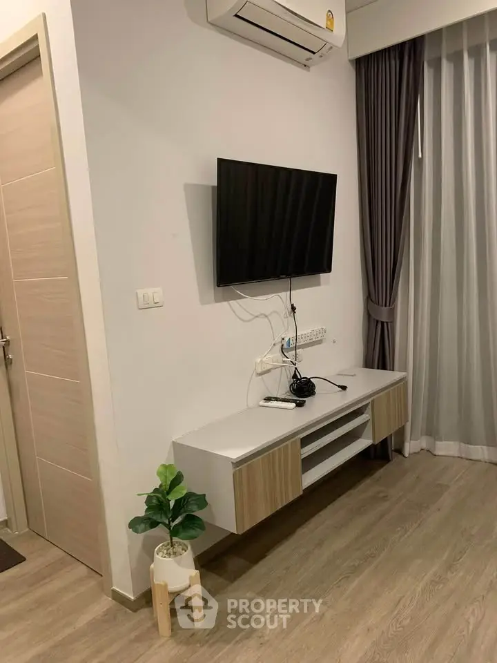 Modern living room with wall-mounted TV and air conditioning, featuring sleek furniture and elegant curtains.