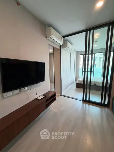 Modern apartment interior with sleek living room and bedroom view, featuring wall-mounted TV and air conditioning.