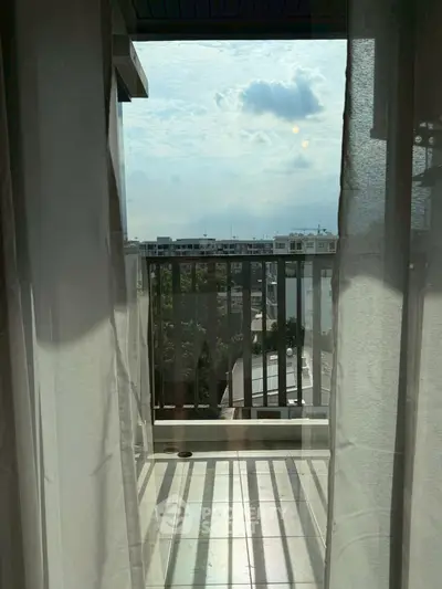Charming balcony with serene city view through sheer curtains, perfect for relaxation.