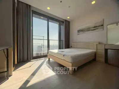 Spacious bedroom with large windows offering stunning city views and modern furnishings.