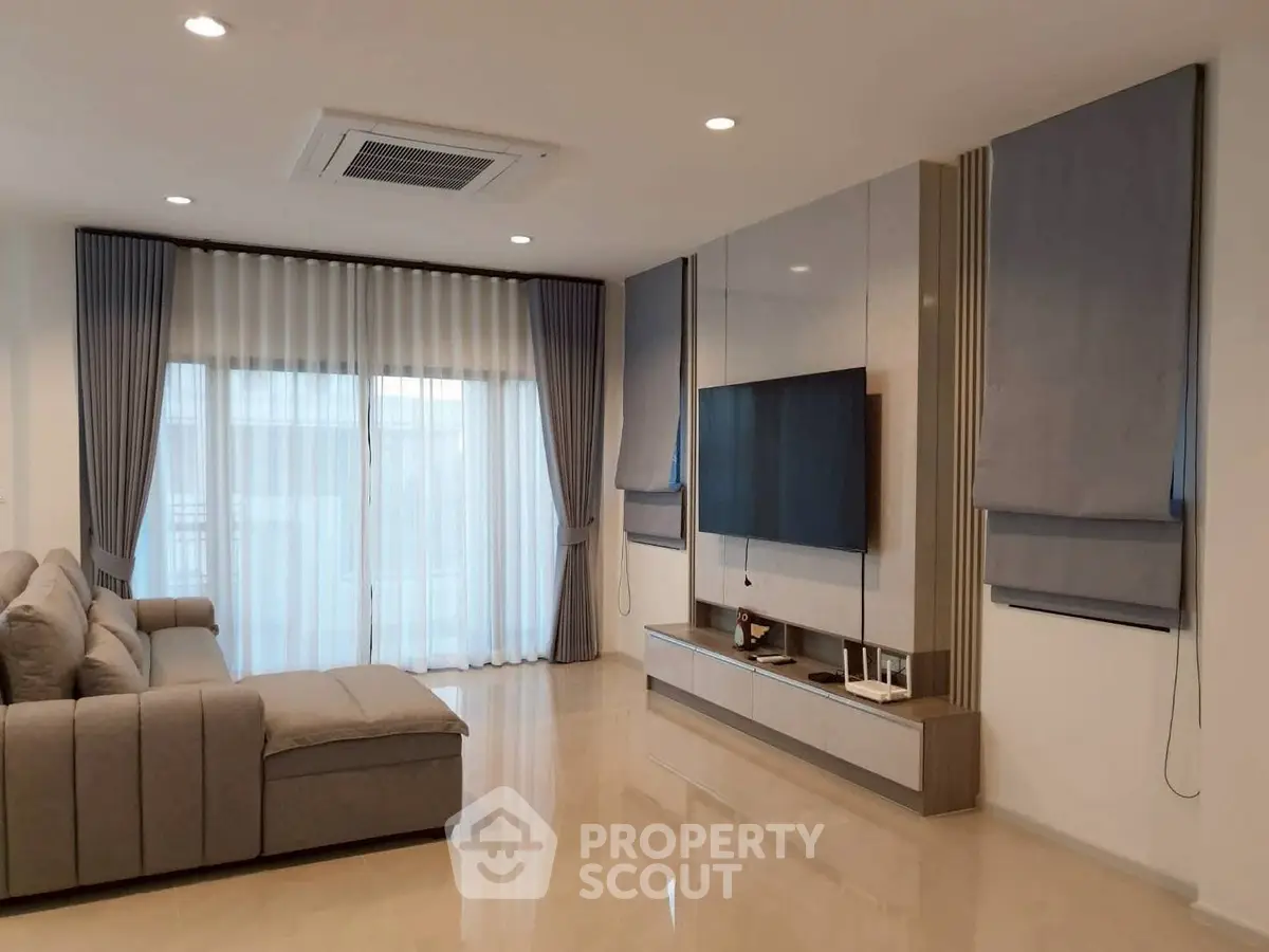 Modern living room with sleek design, large sofa, and wall-mounted TV, perfect for relaxation and entertainment.