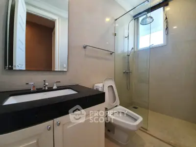 Modern bathroom with glass shower and sleek vanity in luxury apartment