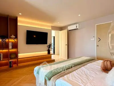 Modern bedroom with stylish decor and wall-mounted TV, featuring cozy lighting and elegant furnishings.