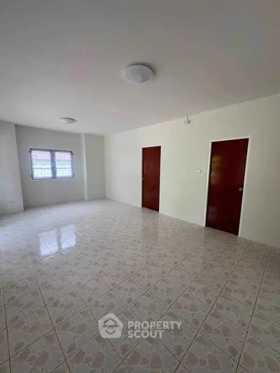 Spacious empty room with tiled flooring and two wooden doors, ideal for customization.