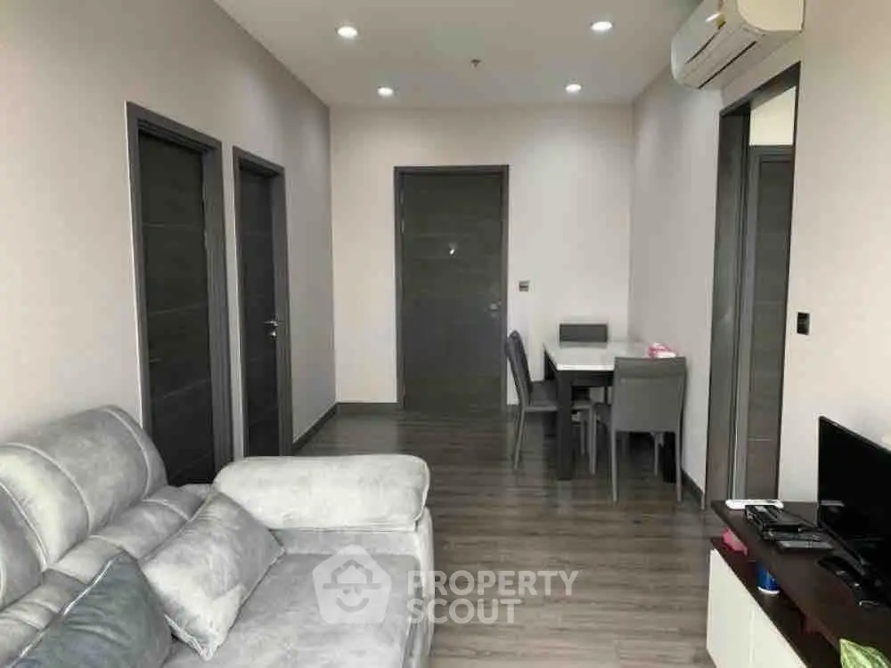 Modern living room with sleek furniture and dining area, featuring a cozy sofa and air conditioning.