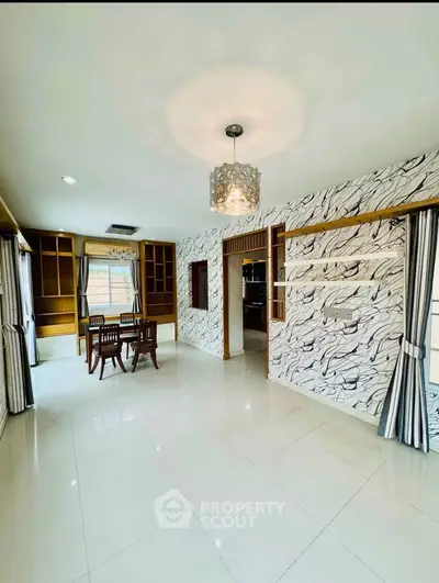 Spacious living room with elegant decor and dining area, featuring modern lighting and large windows.