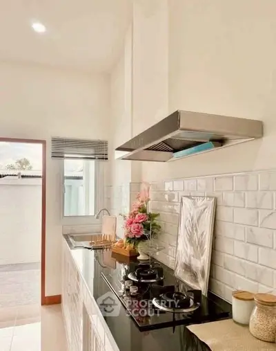 Modern kitchen with sleek gas stove and elegant decor, featuring white subway tiles and natural light.