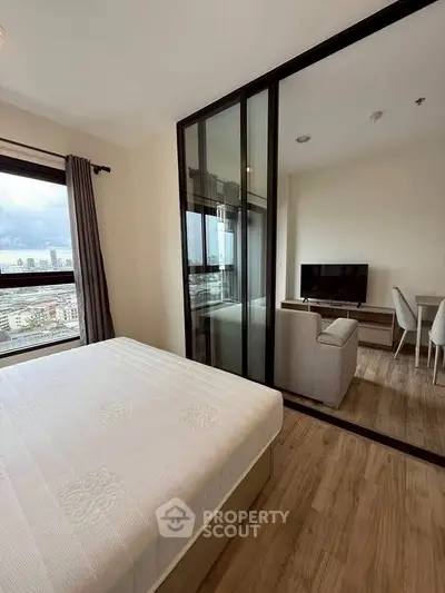 Modern apartment with bedroom and living room, featuring large windows and city view.