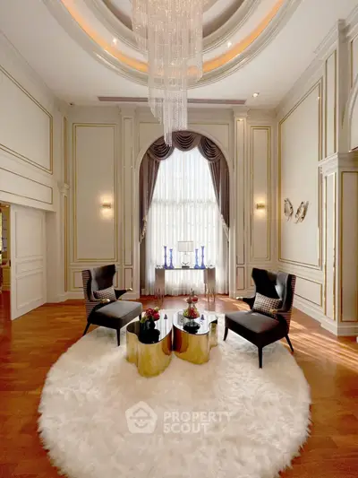 Luxurious living room with high ceiling, elegant chandelier, and plush decor