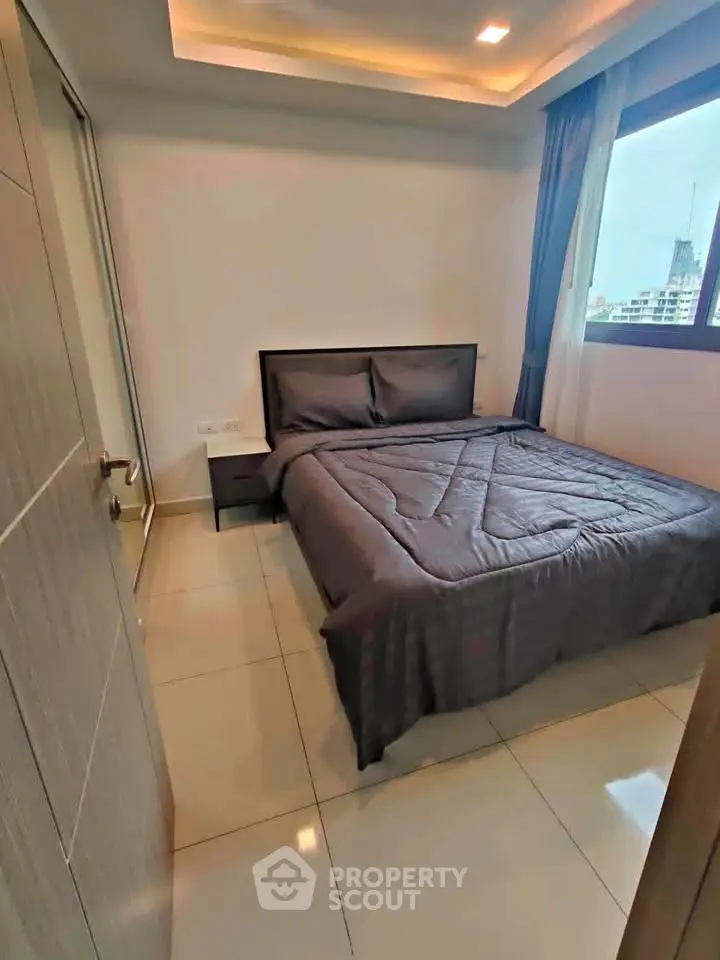 Modern bedroom with sleek design and large window offering city views.