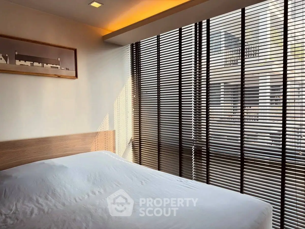 Modern bedroom with large windows and stylish blinds in a contemporary apartment.