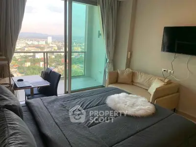 Modern bedroom with stunning city view, cozy seating area, and sleek decor in high-rise apartment.