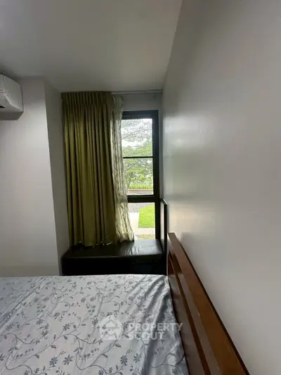 Cozy bedroom with large window and garden view, featuring elegant curtains and a comfortable bed.
