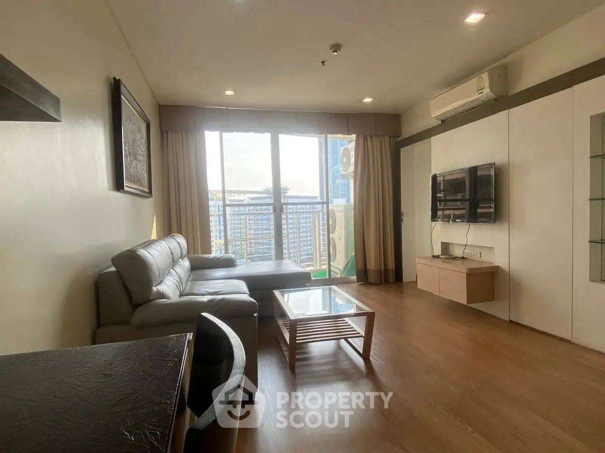 Spacious living room with modern furniture and city view balcony.