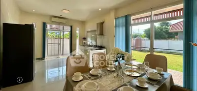 Spacious dining area with garden view, modern kitchen, and elegant table setting in a bright home.