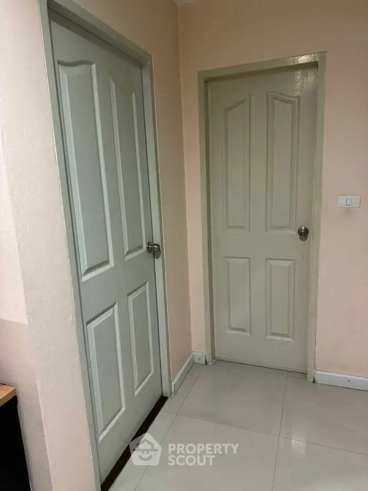 Interior view of a hallway with two closed doors and tiled flooring.