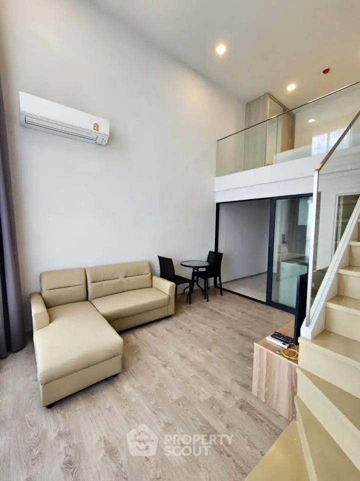 Modern loft-style living room with mezzanine, featuring sleek furniture and ample natural light.