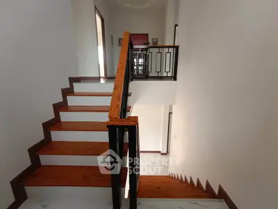 Elegant wooden staircase with modern railing in a bright, spacious home interior.