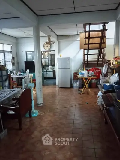 Spacious living area with open layout and staircase, featuring tiled flooring and modern appliances.
