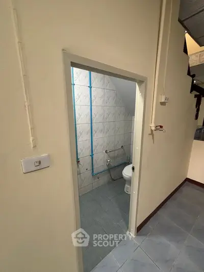 Compact bathroom with tiled walls and floor, featuring basic plumbing fixtures.
