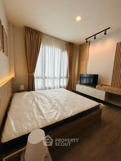 Modern bedroom with stylish decor and natural light, featuring a large bed and sleek TV unit.