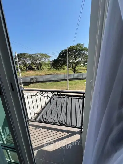 Charming balcony view with lush greenery and clear blue sky, perfect for relaxation.