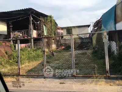 Rustic residential property with fenced yard and overgrown greenery, ideal for renovation.