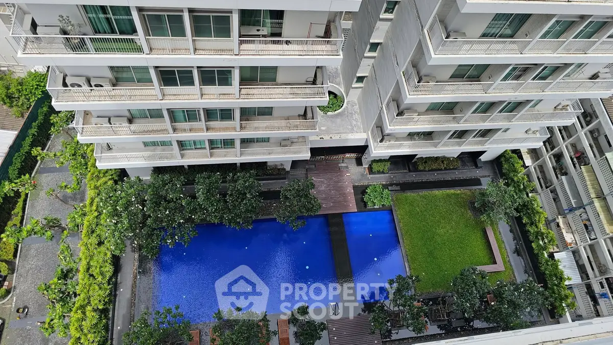 Aerial view of modern apartment complex with pool and garden
